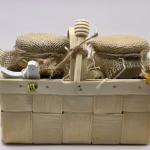 Zdjęcie słoików miodu w drewnianym koszyku z osłonkami.